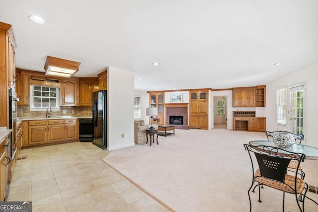 kitchen featuring tasteful backsplash, black appliances, recessed lighting, light countertops, and a brick fireplace