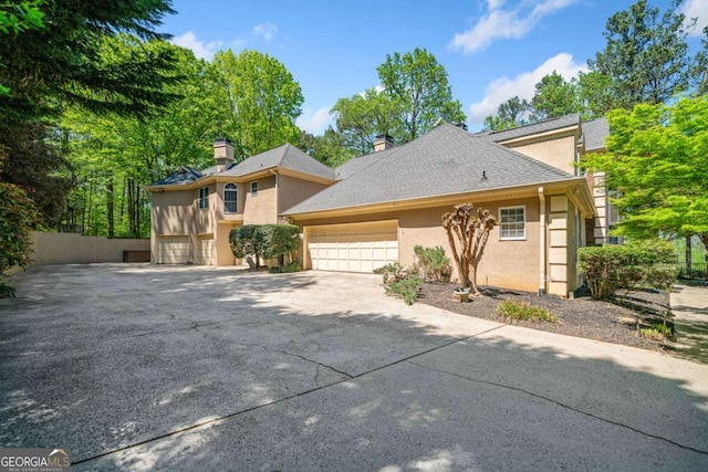 view of front of house with a shingled roof, concrete driveway, stucco siding, and a garage