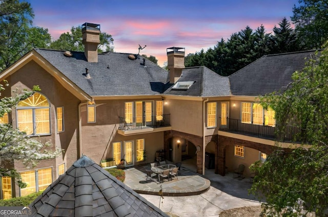 back of property featuring a patio area, stucco siding, a balcony, and a chimney