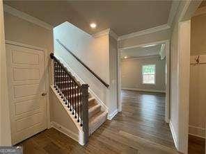 stairway featuring wood finished floors, baseboards, ornamental molding, and recessed lighting