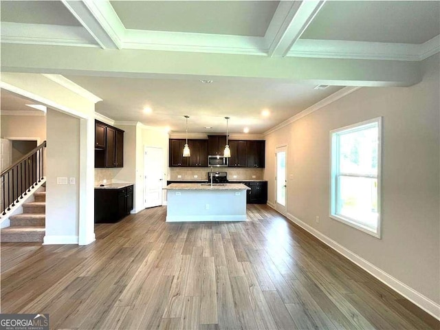 kitchen with stainless steel microwave, dark brown cabinetry, ornamental molding, light countertops, and dark wood-type flooring