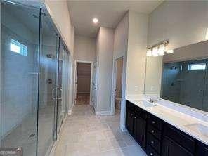 bathroom featuring a sink, double vanity, a stall shower, and recessed lighting