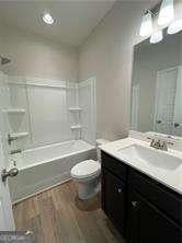 full bathroom featuring toilet, shower / washtub combination, wood finished floors, and vanity