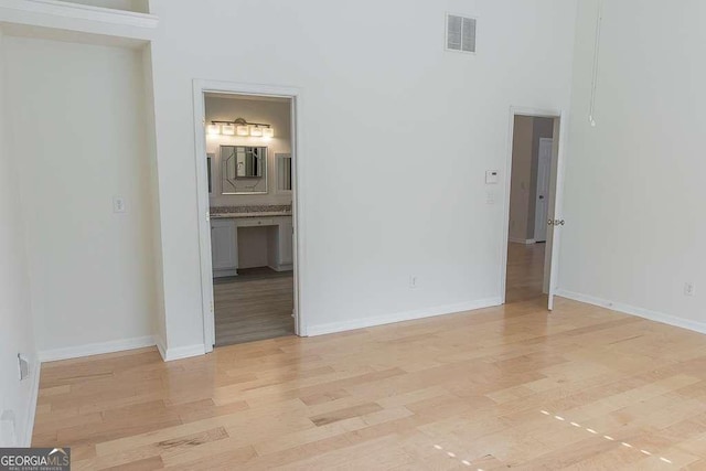 1910 Charleston Oak Cir, Lawrenceville, GA 30043 - unfurnished bedroom featuring visible vents, baseboards, light wood-type flooring, connected bathroom, and a towering ceiling