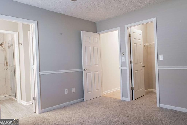 1910 Charleston Oak Cir, Lawrenceville, GA 30043 - unfurnished bedroom featuring ensuite bathroom, a textured ceiling, a closet, carpet flooring, and a walk in closet