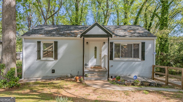bungalow-style house featuring a shingled roof, fence, and brick siding