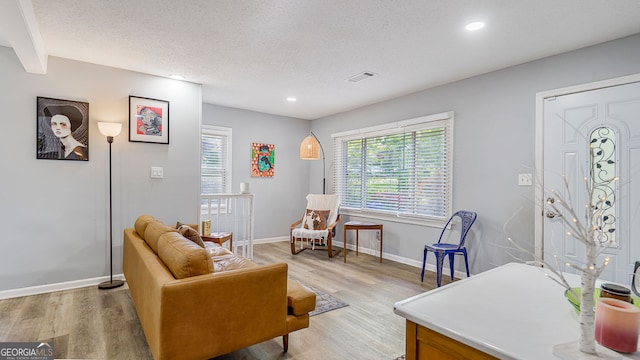 interior space with visible vents, light wood-type flooring, baseboards, and a healthy amount of sunlight