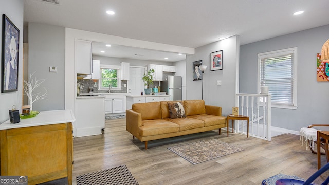 living area with recessed lighting, light wood-style floors, and baseboards