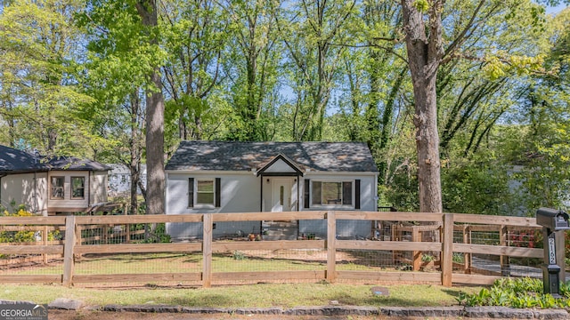 single story home featuring a shingled roof and a fenced front yard
