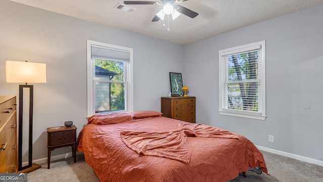 bedroom with light carpet, visible vents, multiple windows, and baseboards