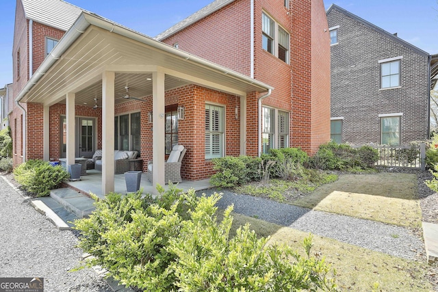 view of side of home featuring a patio, brick siding, and a chimney