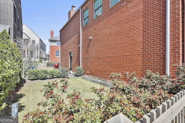 view of side of home with brick siding and fence
