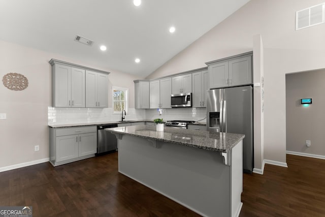 kitchen with stone countertops, gray cabinets, visible vents, appliances with stainless steel finishes, and a sink