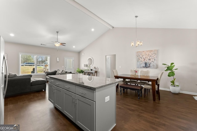 kitchen with light stone counters, open floor plan, a kitchen island, gray cabinetry, and dark wood-type flooring