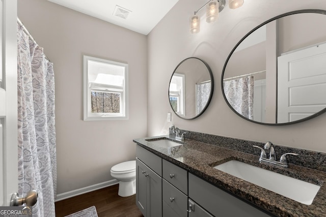 bathroom featuring toilet, wood finished floors, a sink, and visible vents