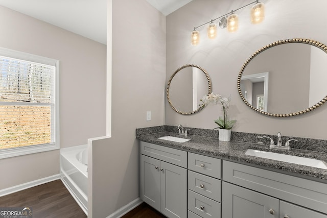 bathroom featuring a sink, baseboards, wood finished floors, and a healthy amount of sunlight