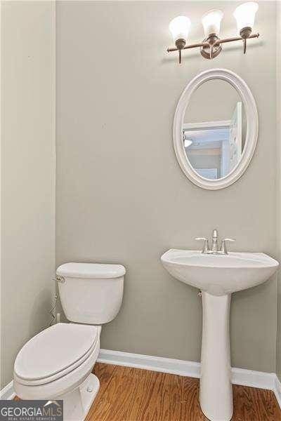 6655 Grove Meadows Ln, Cumming, GA 30028 - half bathroom with toilet, baseboards, wood finished floors, and a sink