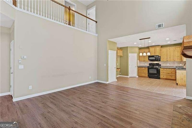 6655 Grove Meadows Ln, Cumming, GA 30028 - unfurnished living room with visible vents, baseboards, light wood finished floors, and a high ceiling