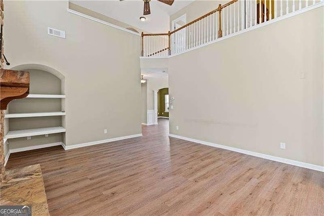 6655 Grove Meadows Ln, Cumming, GA 30028 - unfurnished living room with a high ceiling, a ceiling fan, visible vents, arched walkways, and wood finished floors