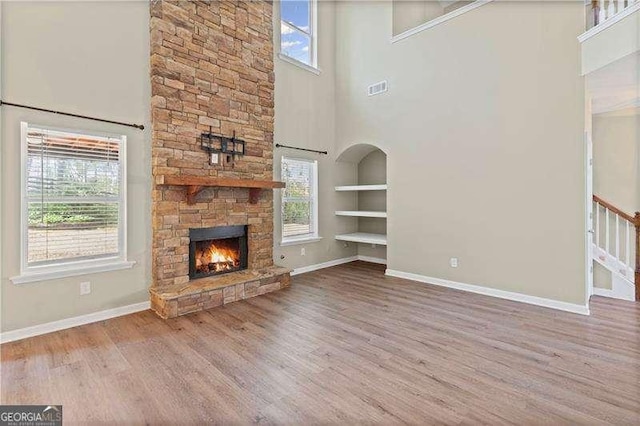 6655 Grove Meadows Ln, Cumming, GA 30028 - unfurnished living room featuring a wealth of natural light, a stone fireplace, a high ceiling, and built in features