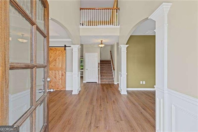 6655 Grove Meadows Ln, Cumming, GA 30028 - entrance foyer featuring arched walkways, a decorative wall, light wood-type flooring, stairs, and a wainscoted wall