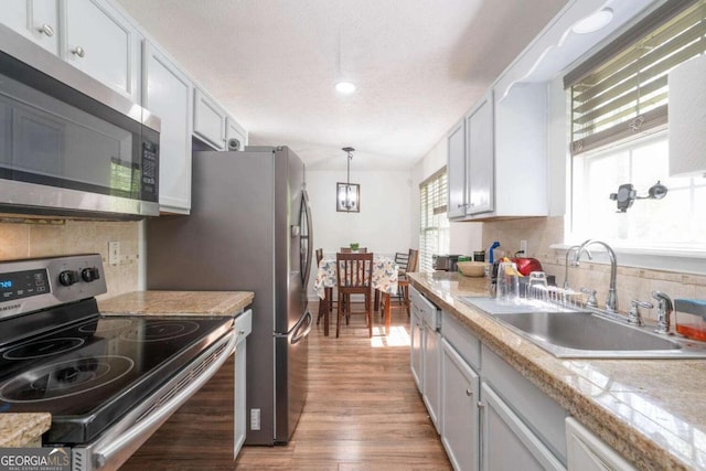 166 Rustin Dr, Dallas, GA 30157 - kitchen featuring stainless steel appliances, light wood-style floors, tasteful backsplash, light countertops, and pendant lighting
