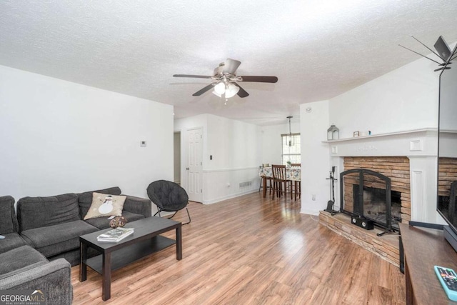 166 Rustin Dr, Dallas, GA 30157 - living room featuring a ceiling fan, a textured ceiling, light wood finished floors, and a fireplace