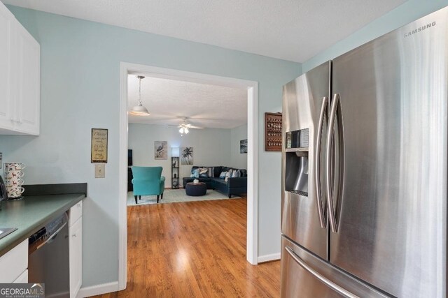 kitchen with light wood-style floors, ceiling fan, white cabinets, dishwasher, and stainless steel fridge