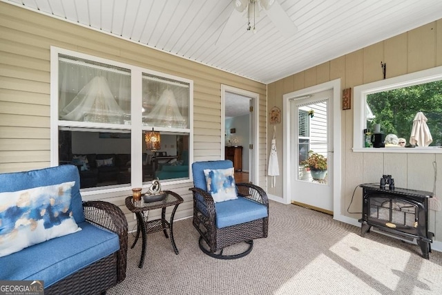 sunroom / solarium featuring wood walls, a ceiling fan, and carpet flooring