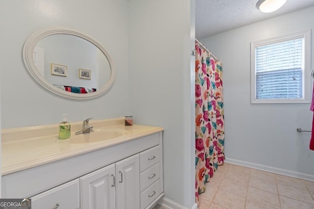 bathroom with tile patterned flooring, baseboards, vanity, and a textured ceiling