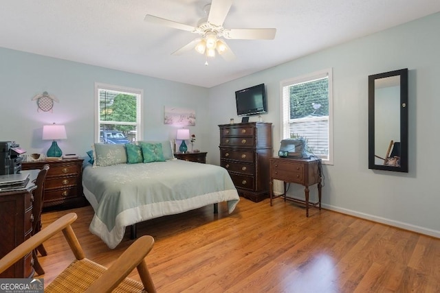 bedroom with wood finished floors, baseboards, and multiple windows