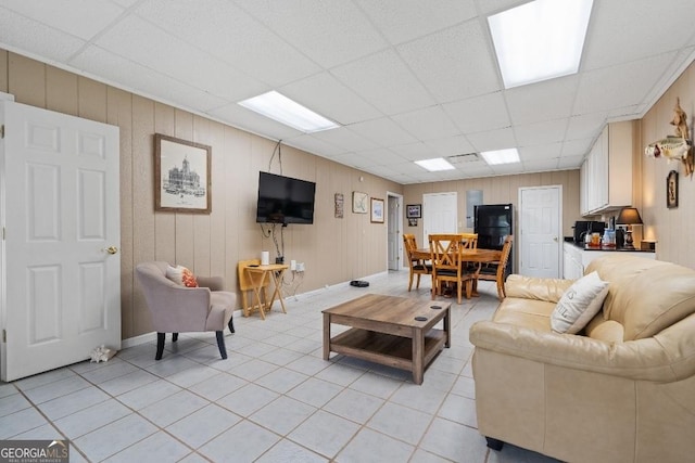 living area with light tile patterned floors and a paneled ceiling