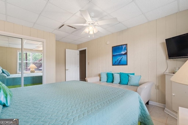 bedroom featuring a paneled ceiling, access to exterior, light tile patterned flooring, and ceiling fan