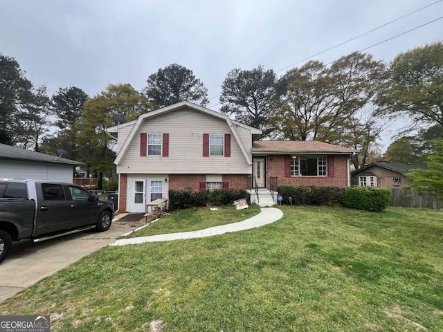 tri-level home featuring a front yard, brick siding, a gambrel roof, and fence