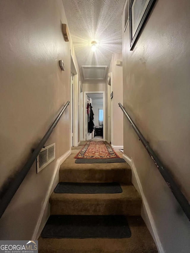staircase with visible vents, baseboards, carpet, and a textured ceiling