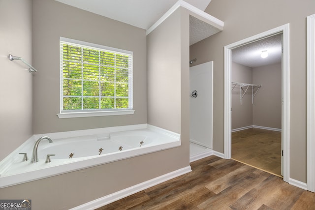 3571 Oakshire Way SE, Atlanta, GA 30354 - full bathroom with a walk in closet, a stall shower, wood finished floors, and a garden tub