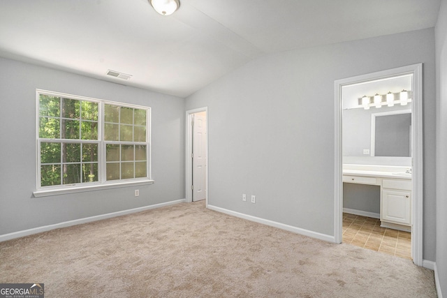 1728 Devon Dr SW, Atlanta, GA 30311 - unfurnished bedroom featuring ensuite bath, vaulted ceiling, light carpet, baseboards, and visible vents