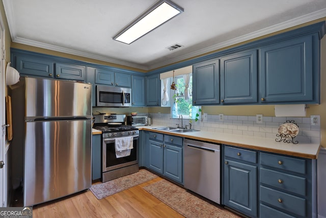 2675 Dacula Ridge Dr, Dacula, GA 30019 - kitchen featuring appliances with stainless steel finishes, blue cabinetry, light wood-type flooring, light countertops, and ornamental molding