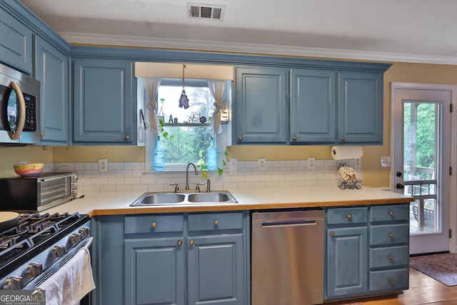 2675 Dacula Ridge Dr, Dacula, GA 30019 - kitchen featuring appliances with stainless steel finishes, blue cabinets, crown molding, and tasteful backsplash