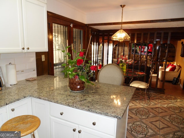 4213 Janice Dr, Atlanta, GA 30337 - kitchen with hanging light fixtures, white cabinets, an inviting chandelier, decorative backsplash, and light stone counters
