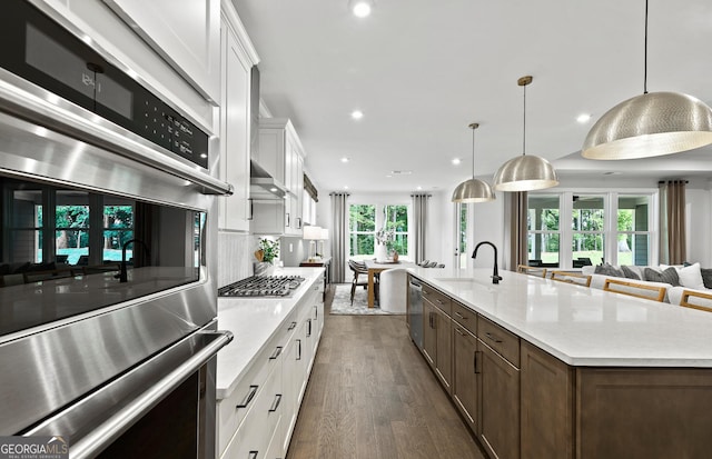 kitchen featuring open floor plan, dark wood-style floors, light countertops, white cabinets, and wall chimney exhaust hood