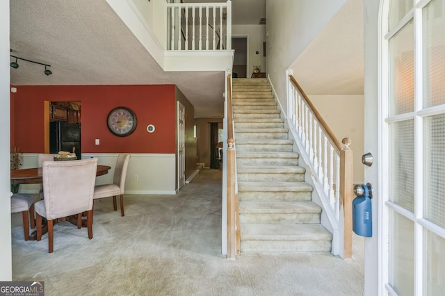stairs with carpet floors and a textured ceiling