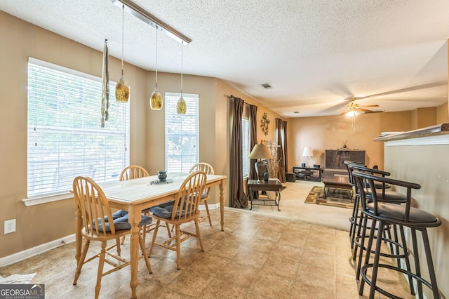 dining room with visible vents, a ceiling fan, a fireplace, and a textured ceiling