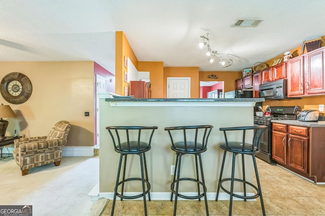 kitchen featuring a kitchen breakfast bar, a textured ceiling, dark brown cabinets, visible vents, and black appliances