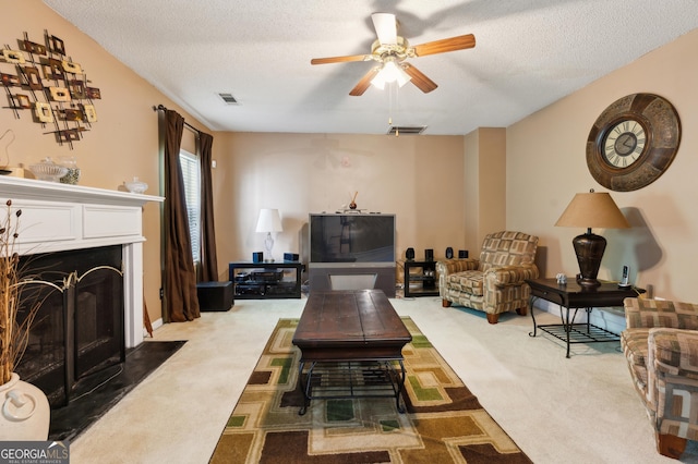 living room with carpet floors, ceiling fan, visible vents, and a fireplace with flush hearth