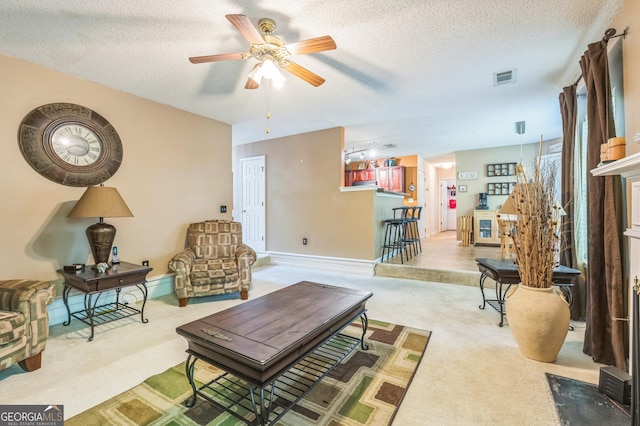 carpeted living room with a textured ceiling, baseboards, a ceiling fan, and visible vents