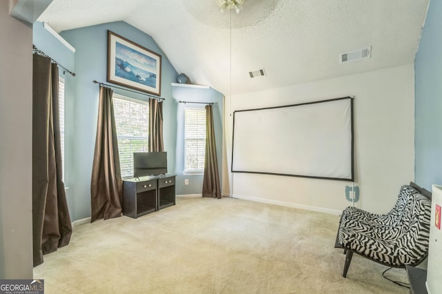 carpeted home theater featuring visible vents, a textured ceiling, baseboards, and lofted ceiling