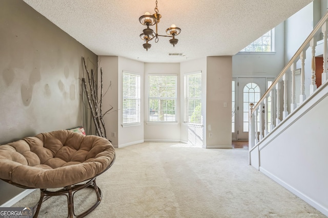 living area featuring a wealth of natural light, carpet, visible vents, and a textured ceiling