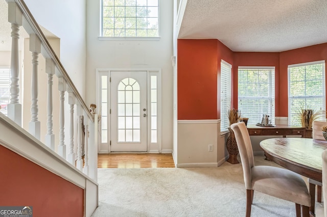 carpeted entryway with stairway, a textured ceiling, and baseboards