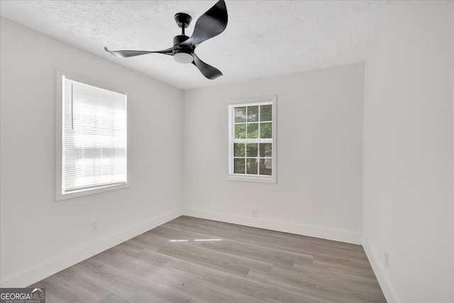 empty room with a textured ceiling, a ceiling fan, wood finished floors, and baseboards